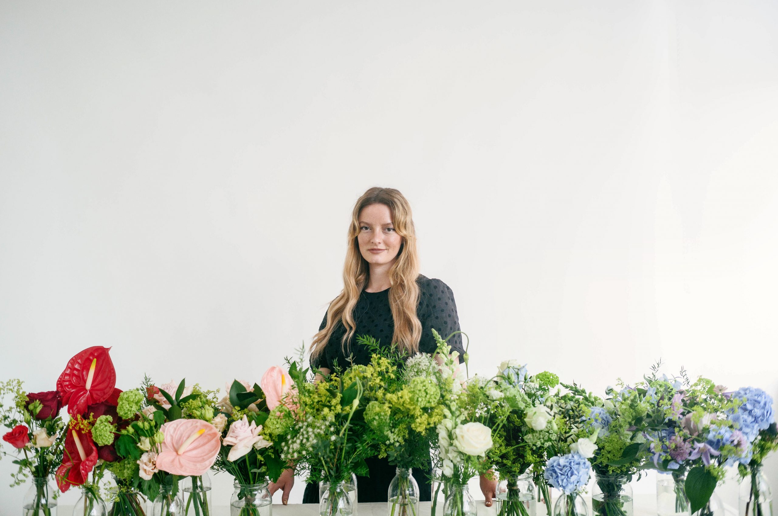 Dakota Blue Richards standing behind a selection of bespoke luxury flowers